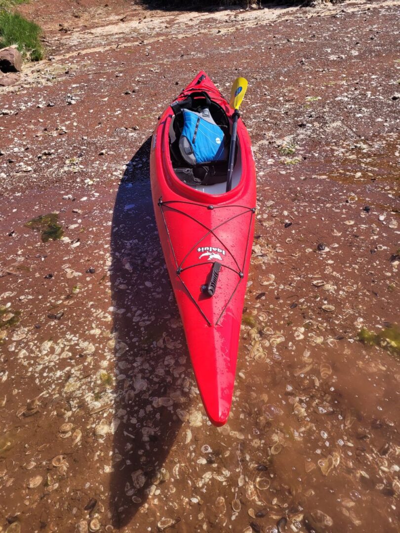 A Red Color Canoe on a River Bed Area One