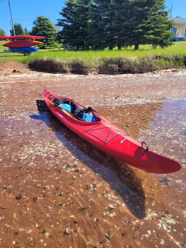 A Red Color Canoe on the River Bed Placed Cross